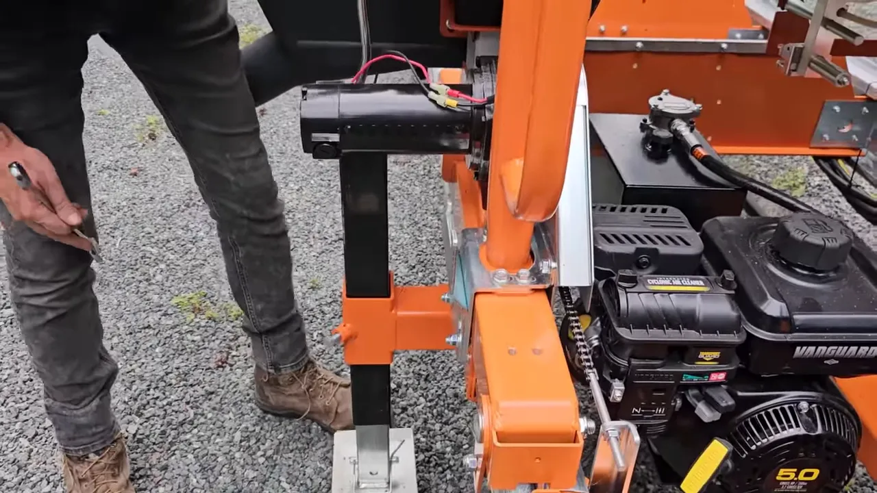 Person adjusting trailer jack and working on sawmill engine and supports during loading