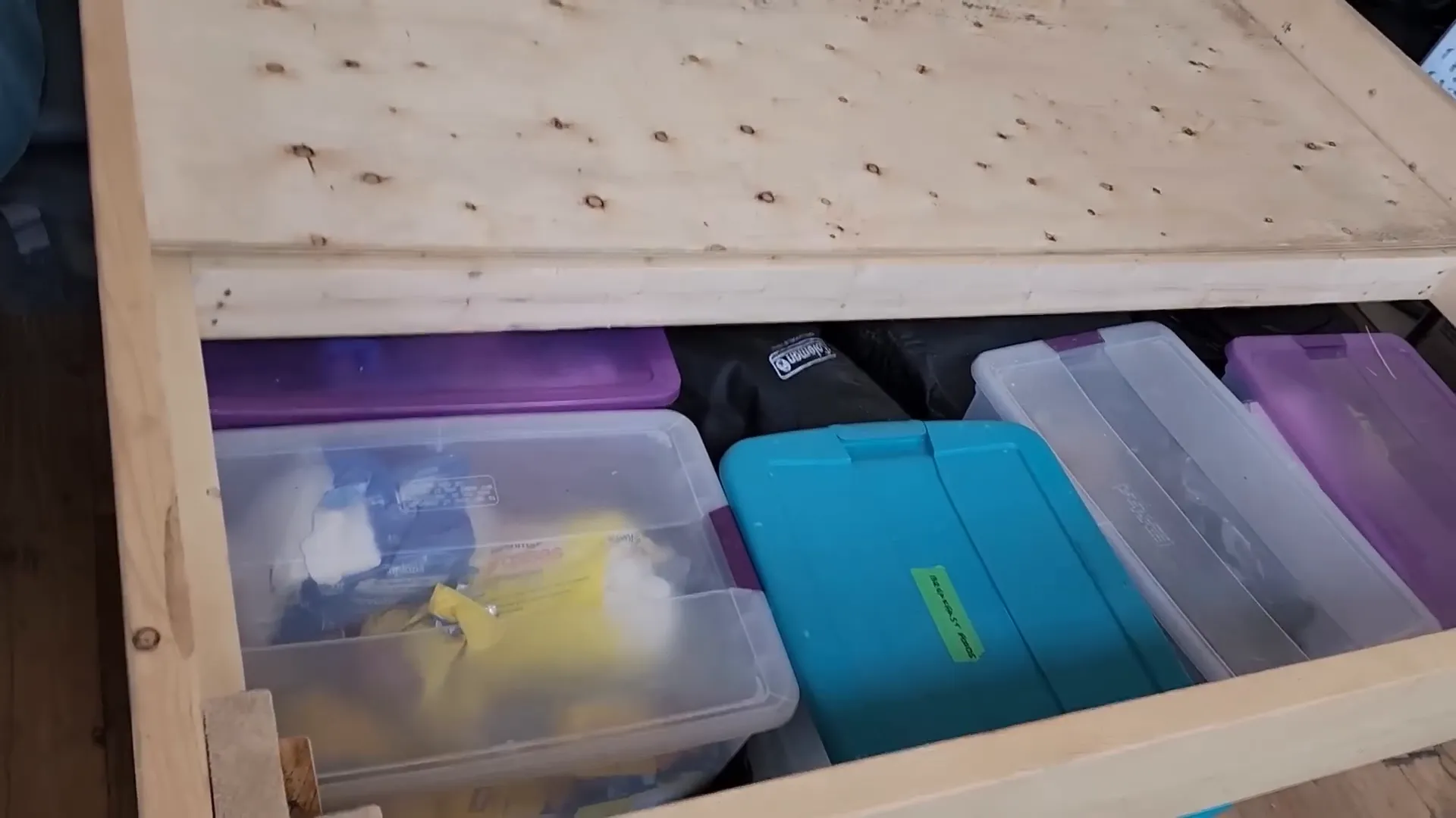 Several bins arranged under a bed frame