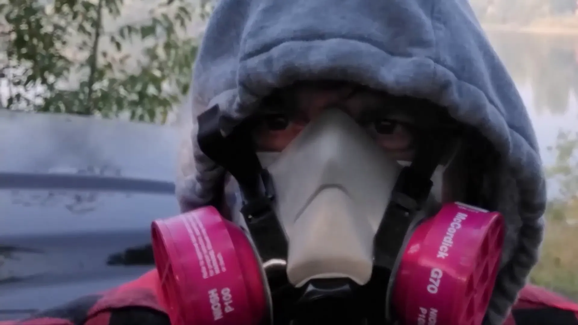 A woman in a hoodie and gas mask