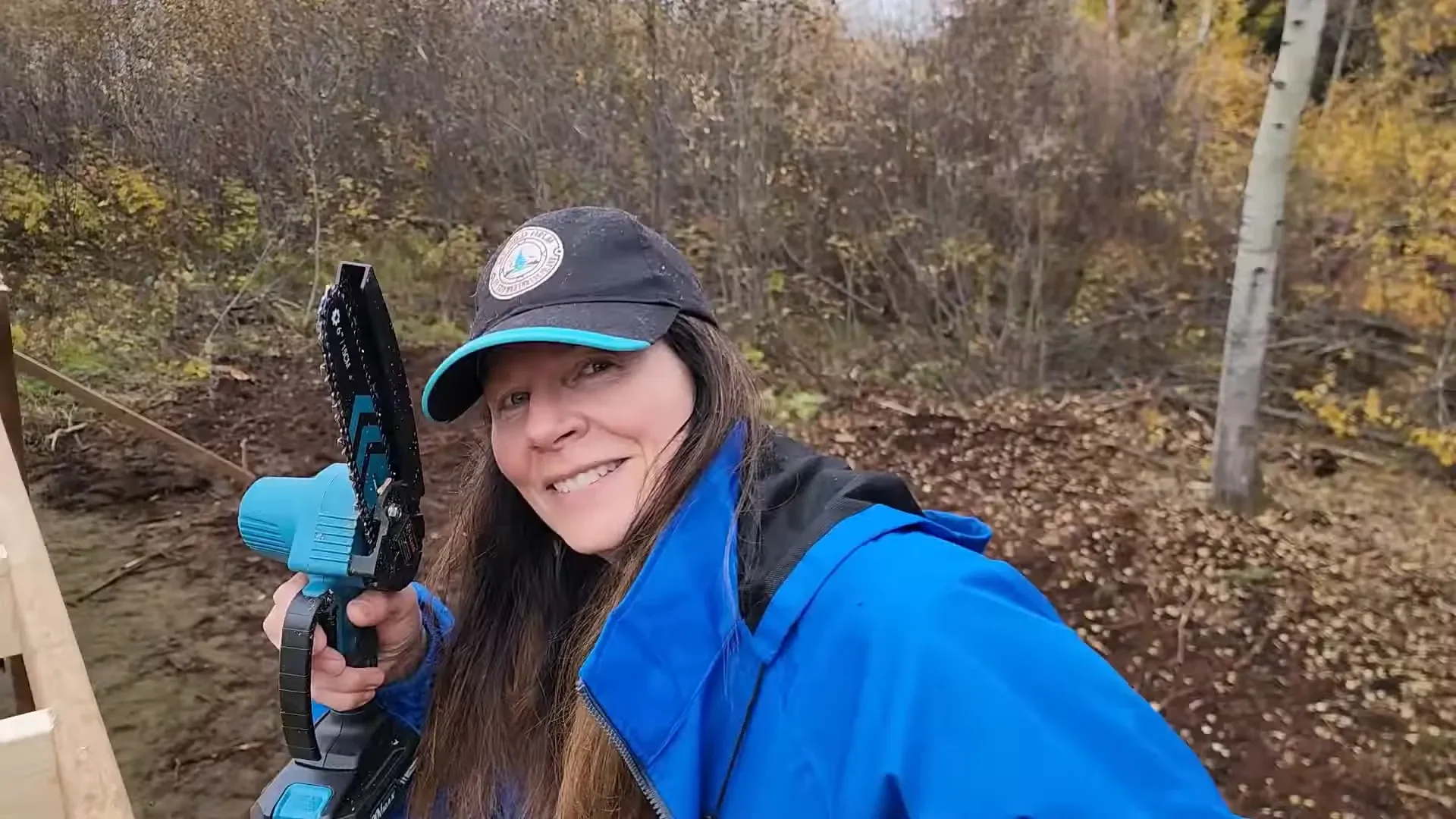 Melodi trimming a post with a chainsaw