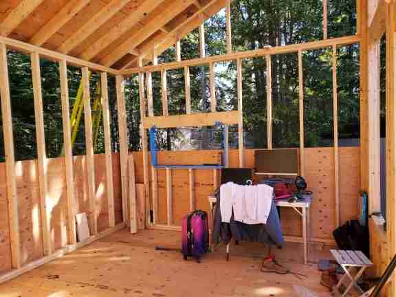 Tiny cabin under construction. Open framing with roof decking on.