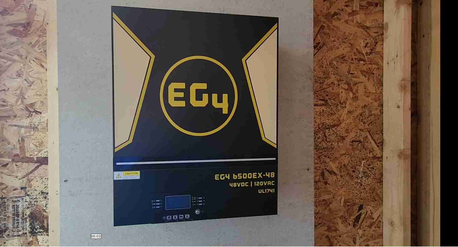 An eg4 6500ex inverter hanging on a piece of cement board in a inverter shed
