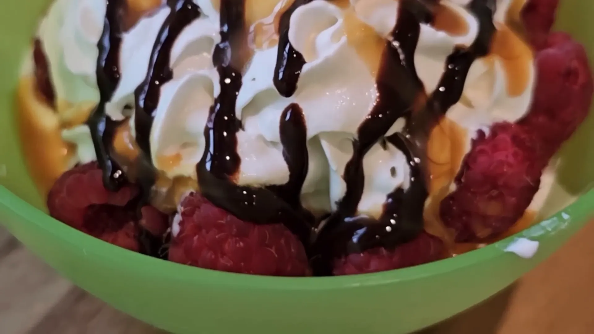 Close up of an amazing desert with fresh raspberries, whipped cream and chocolate and caramel drizzle