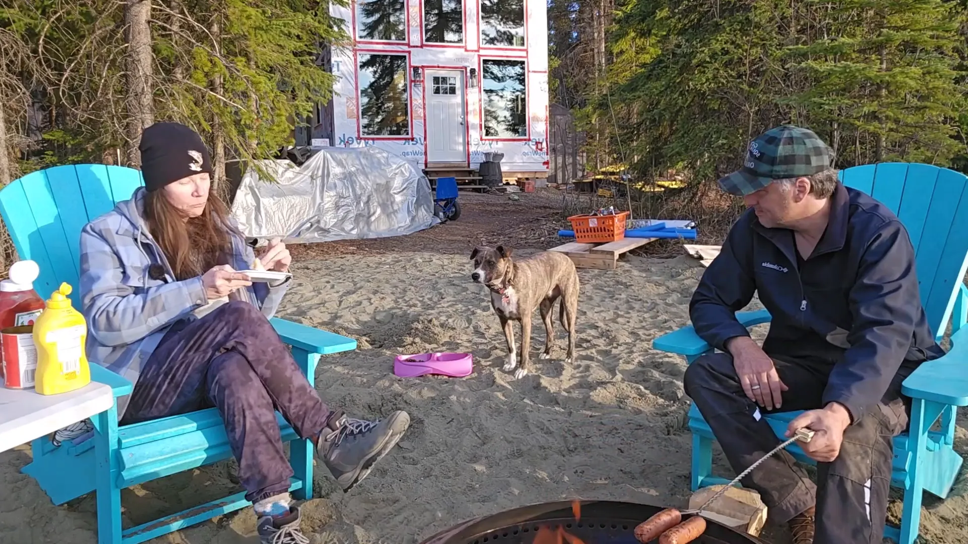 Man and woman enjoying hotdogs by the fire