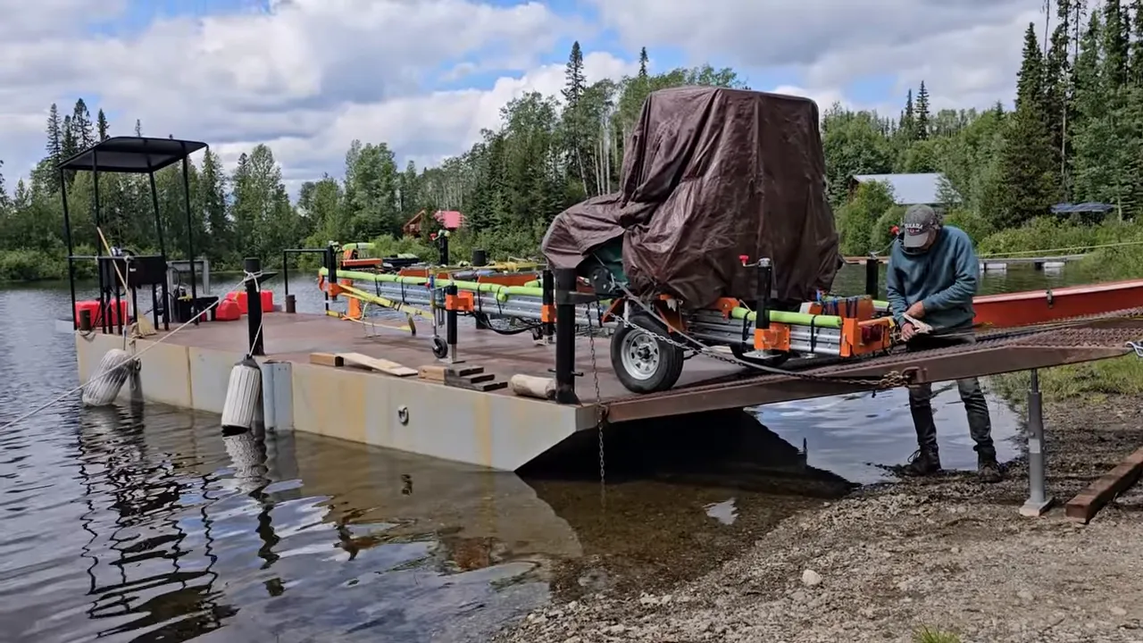 One Slip and Our New Sawmill Falls Into the Water! - S4 Ep11 7 Norwood portable sawmill secured on a barge with a crew member tightening straps on the ramp