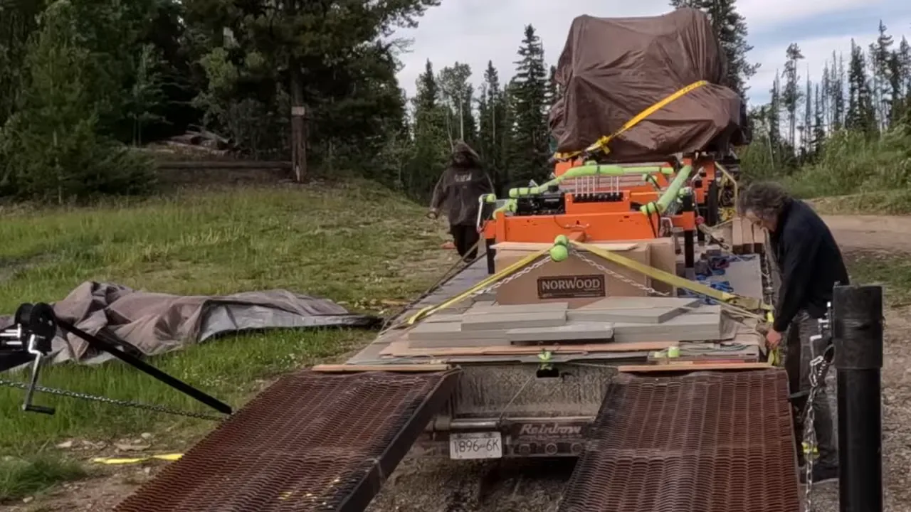 One Slip and Our New Sawmill Falls Into the Water! - S4 Ep11 4 Close view of norwood sawmill on trailer with yellow ratchet straps and a person tightening them