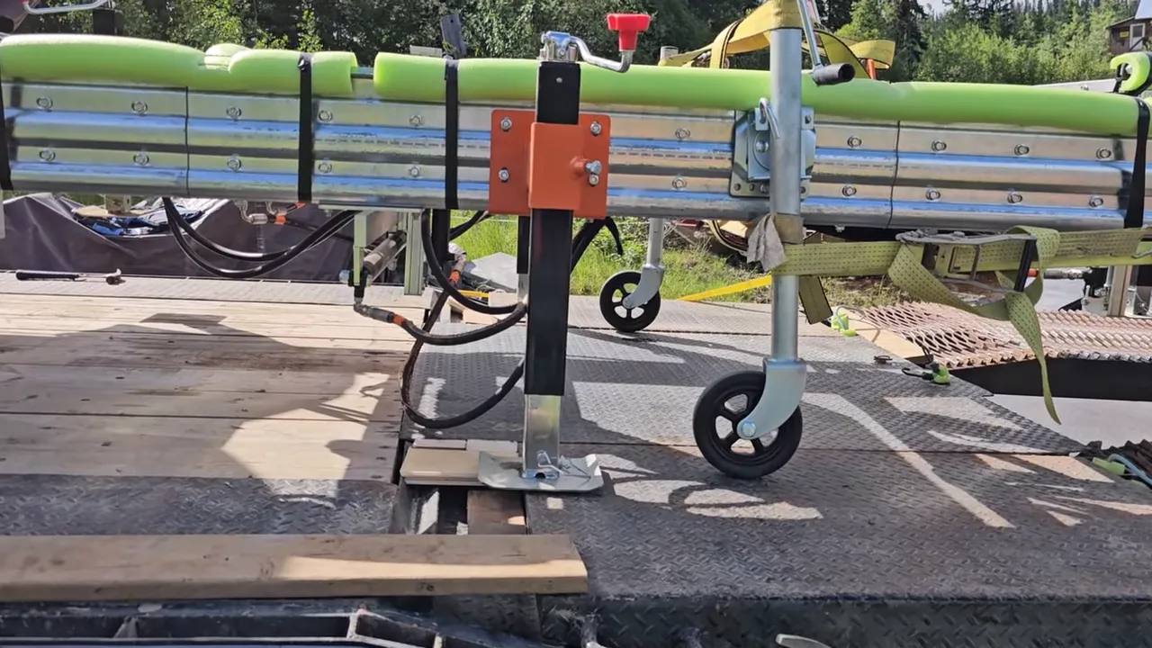 One Slip and Our New Sawmill Falls Into the Water! - S4 Ep11 6 Screw jack foot resting on wooden blocks beside a metal ramp with the portable sawmill frame overhead