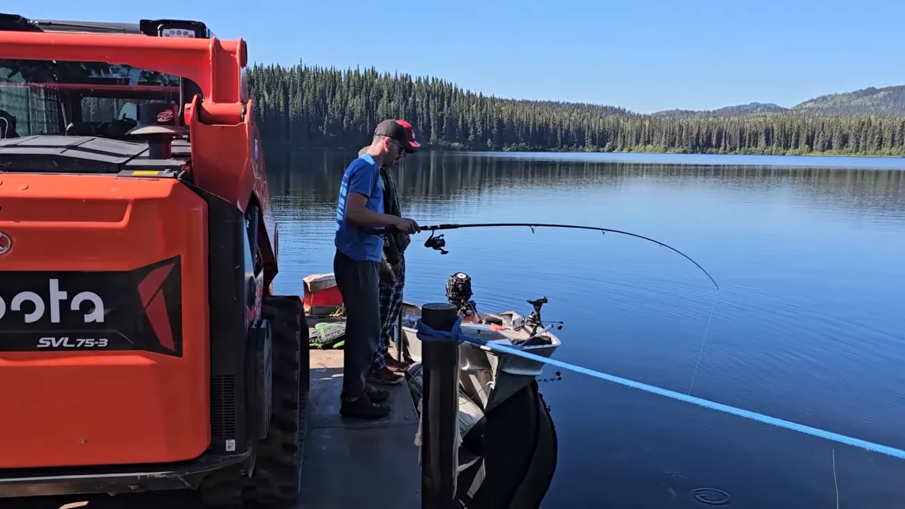 Man on a skiff at a dock next to a barge on a calm remote lake
