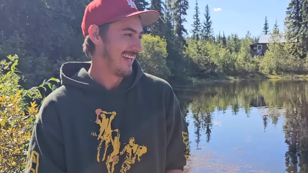Smiling man standing by a calm remote island lake and shoreline greenery