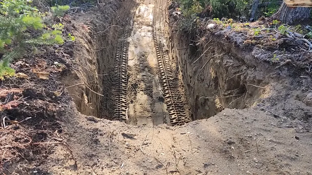 Deep excavated trench with heavy equipment track marks for underground battery bunker