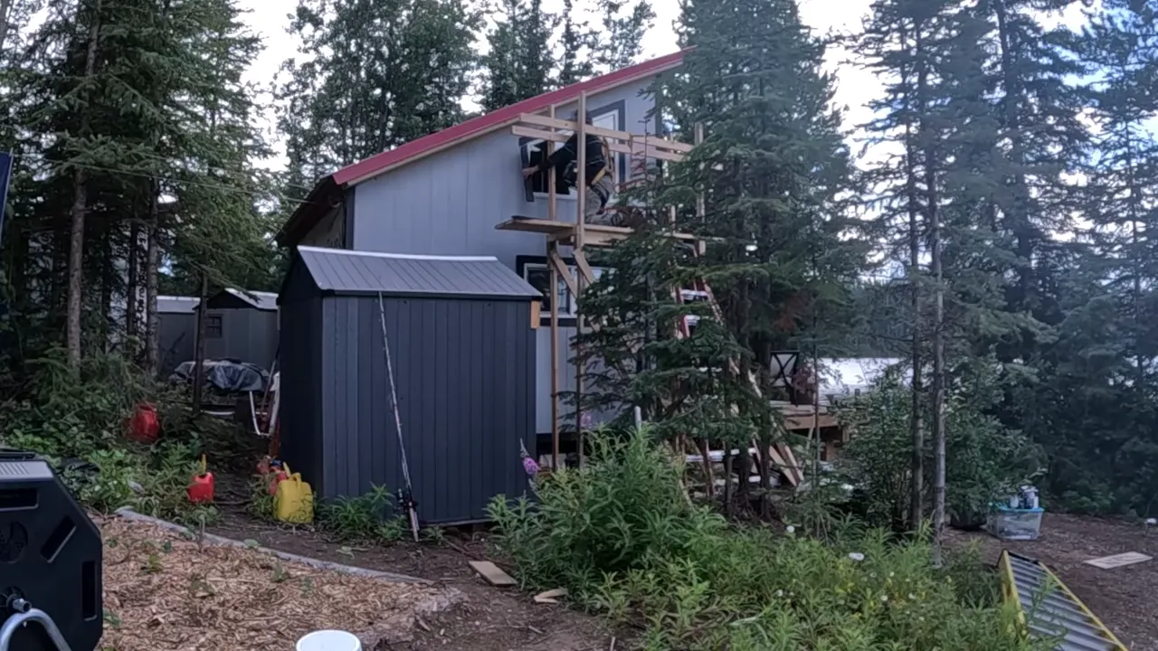 Worker on custom wooden scaffold finishing a trapezoid window and trim on the cabin
