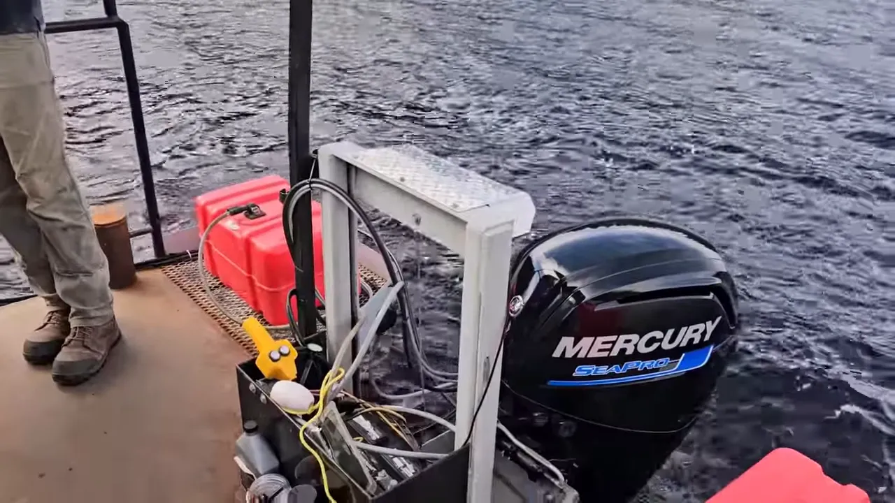 Close-up of a mercury seapro outboard on a barge with a red fuel can, wiring and hoses on the deck