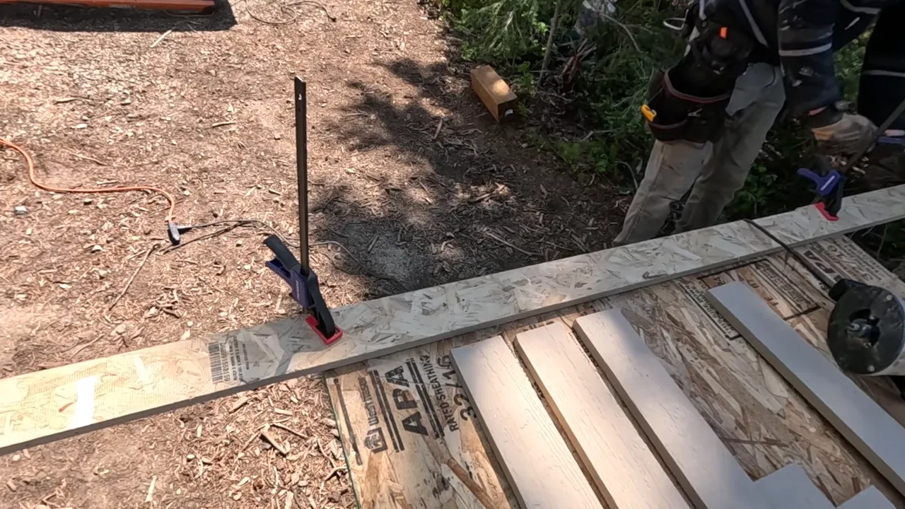 Off Grid Life Canada: Building a Tiny Cabin on Our Remote Island – Biggest Transformation Yet! - S4 Ep8 7 Clamps and siding boards arranged on osb sheathing creating a makeshift outdoor workbench