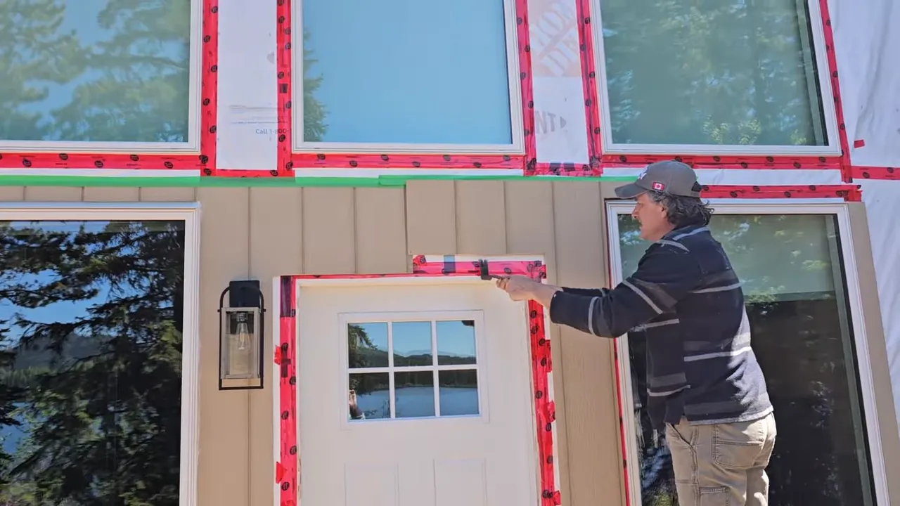 Off Grid Life Canada: Building a Tiny Cabin on Our Remote Island – Biggest Transformation Yet! - S4 Ep8 1 Person aligning siding above the front door with a green tape line marking the lower course for the upper siding.