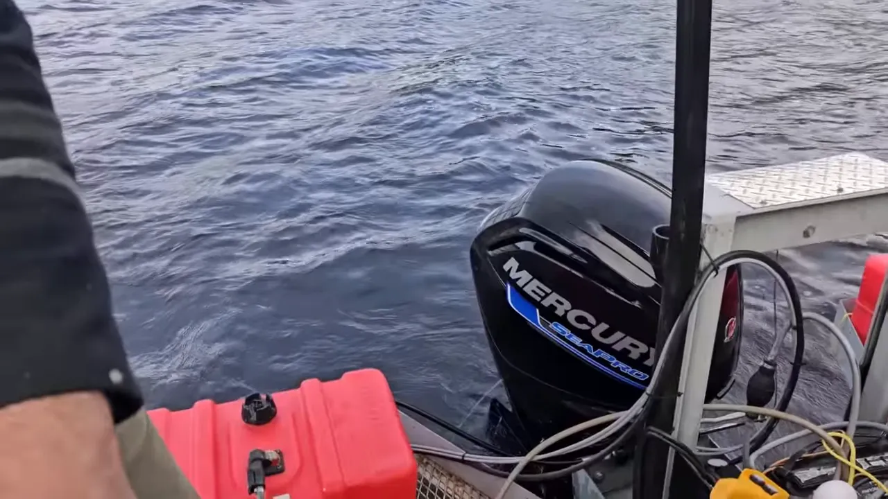Outboard motor (mercury) and red fuel tank on the barge deck with ropes and cables nearby